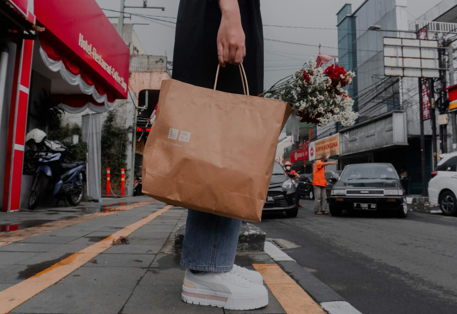 Someone carrying a paper bag of rescued food along a city street