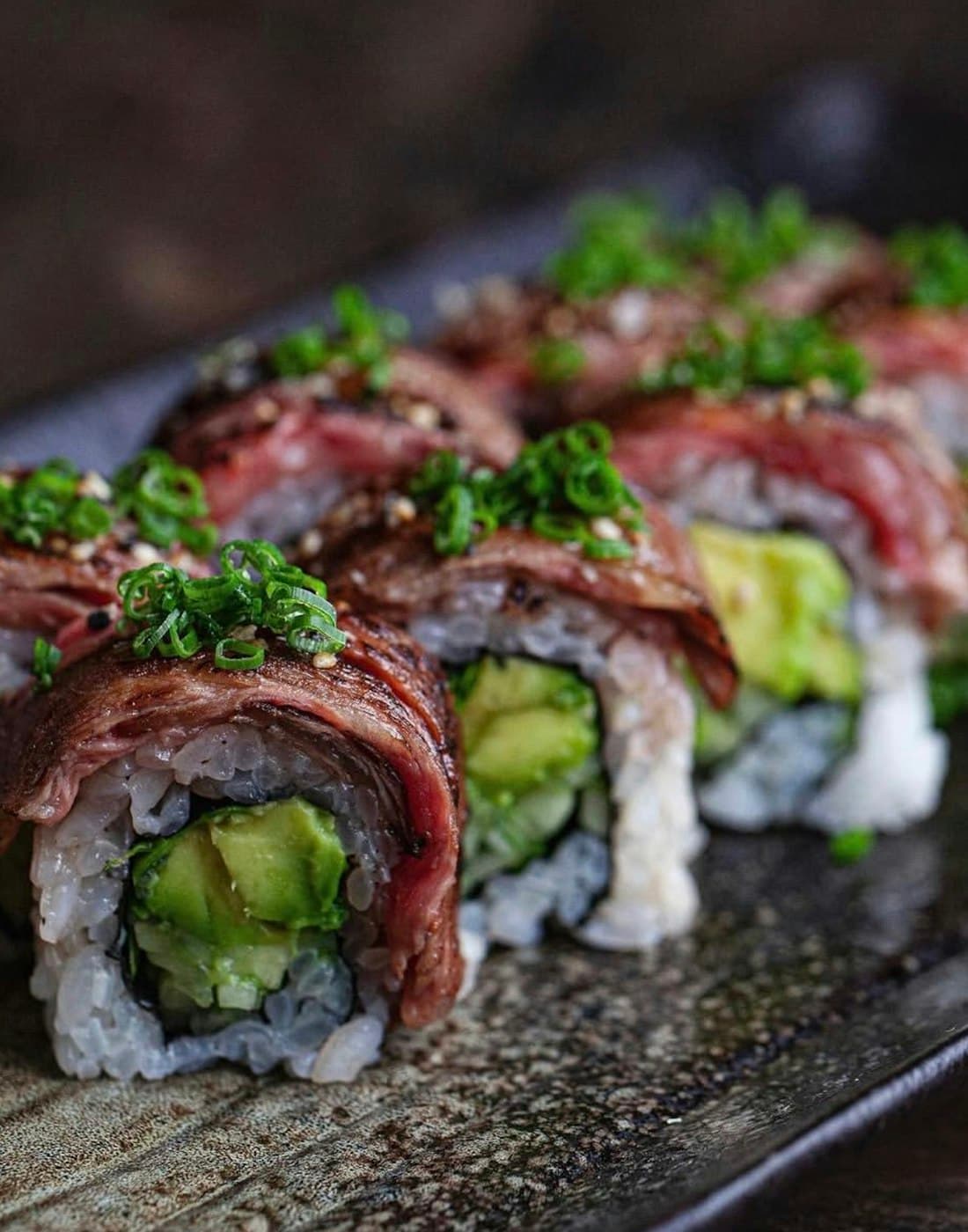 Close-up of sushi rolls topped with avocado