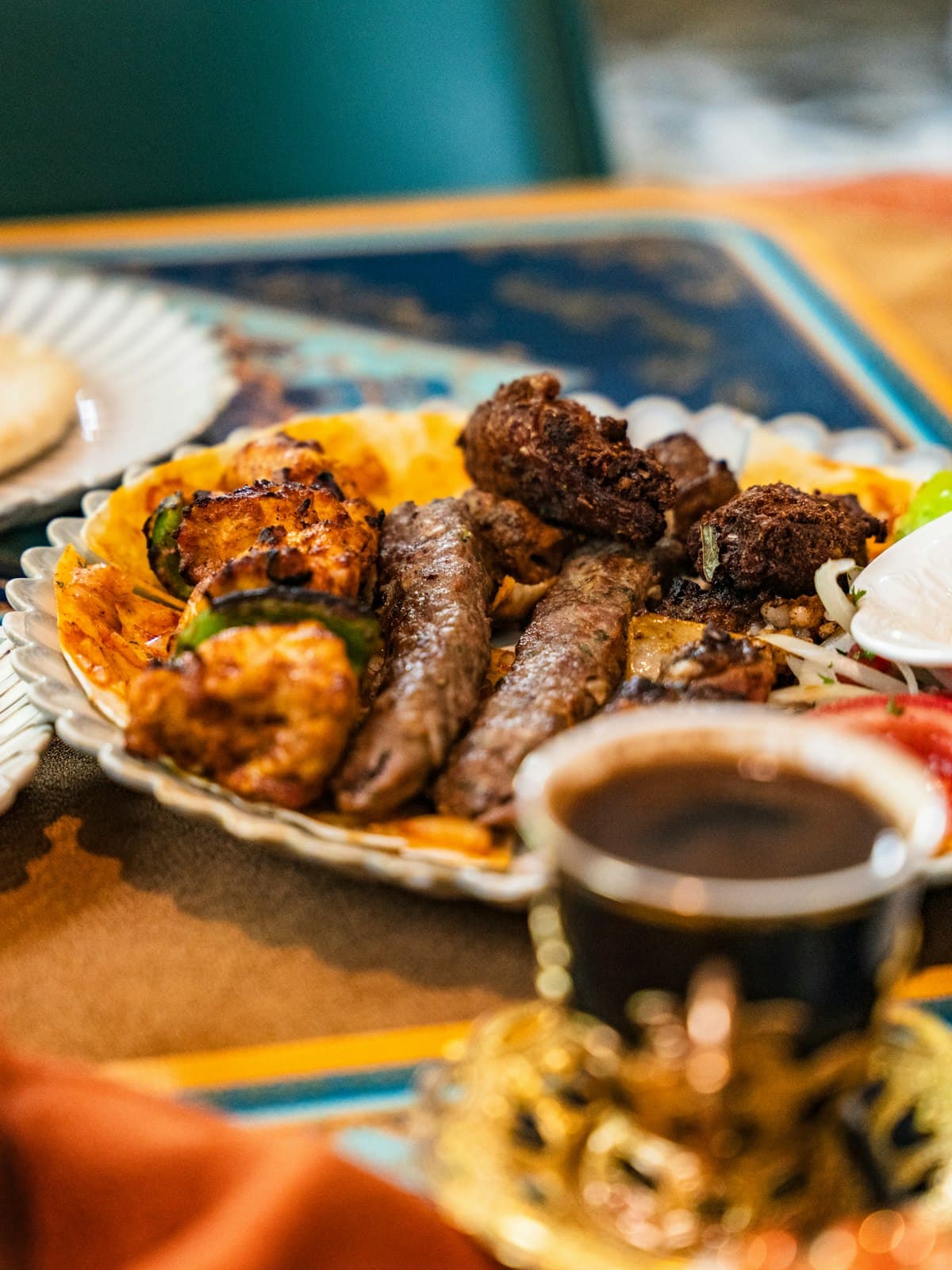 A restaurant platter of grilled kebabs, flatbread and mezze with a cup of Arabic coffee