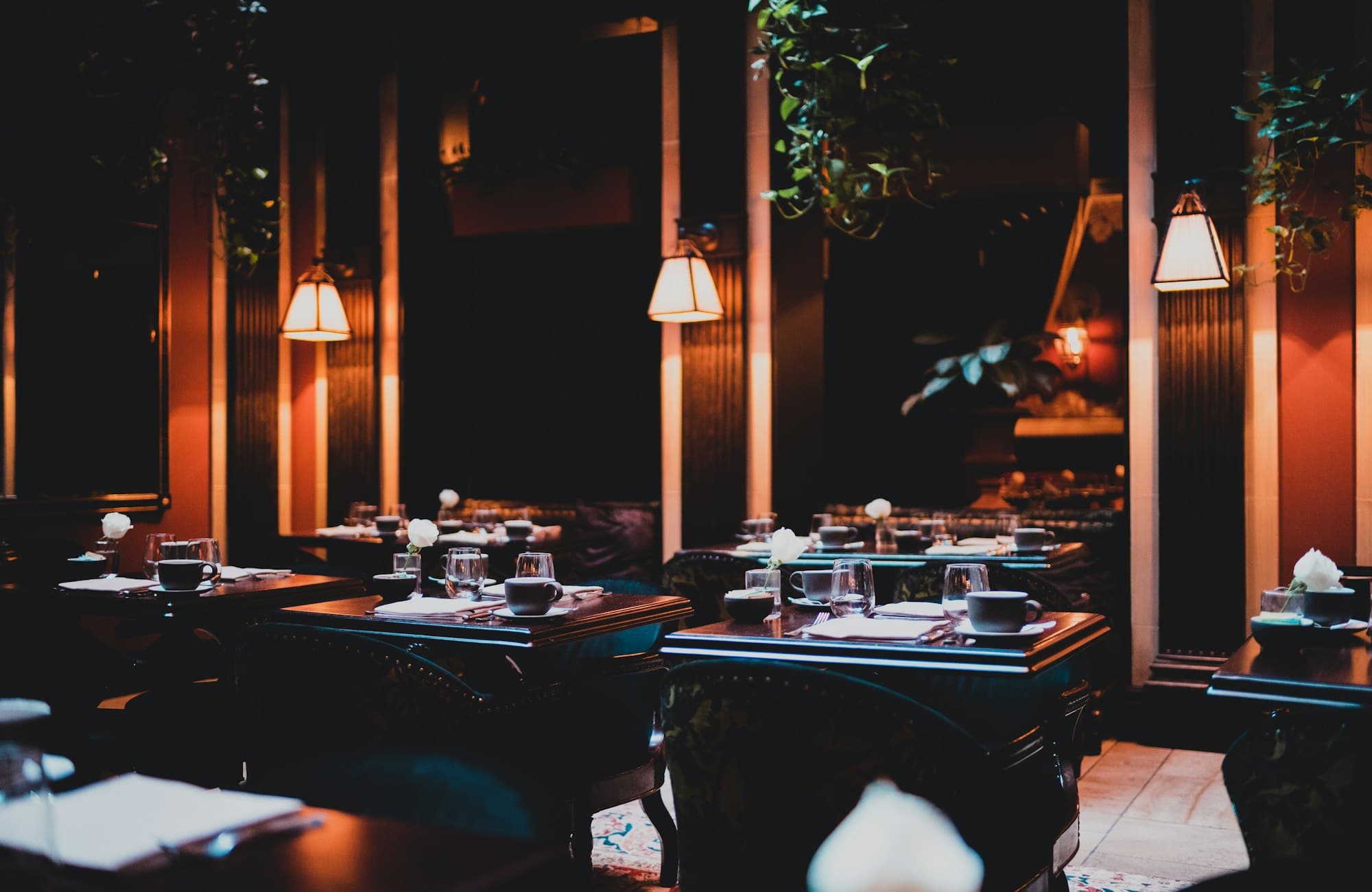 A restaurant dining room lit by warm hanging lamps at the end of service