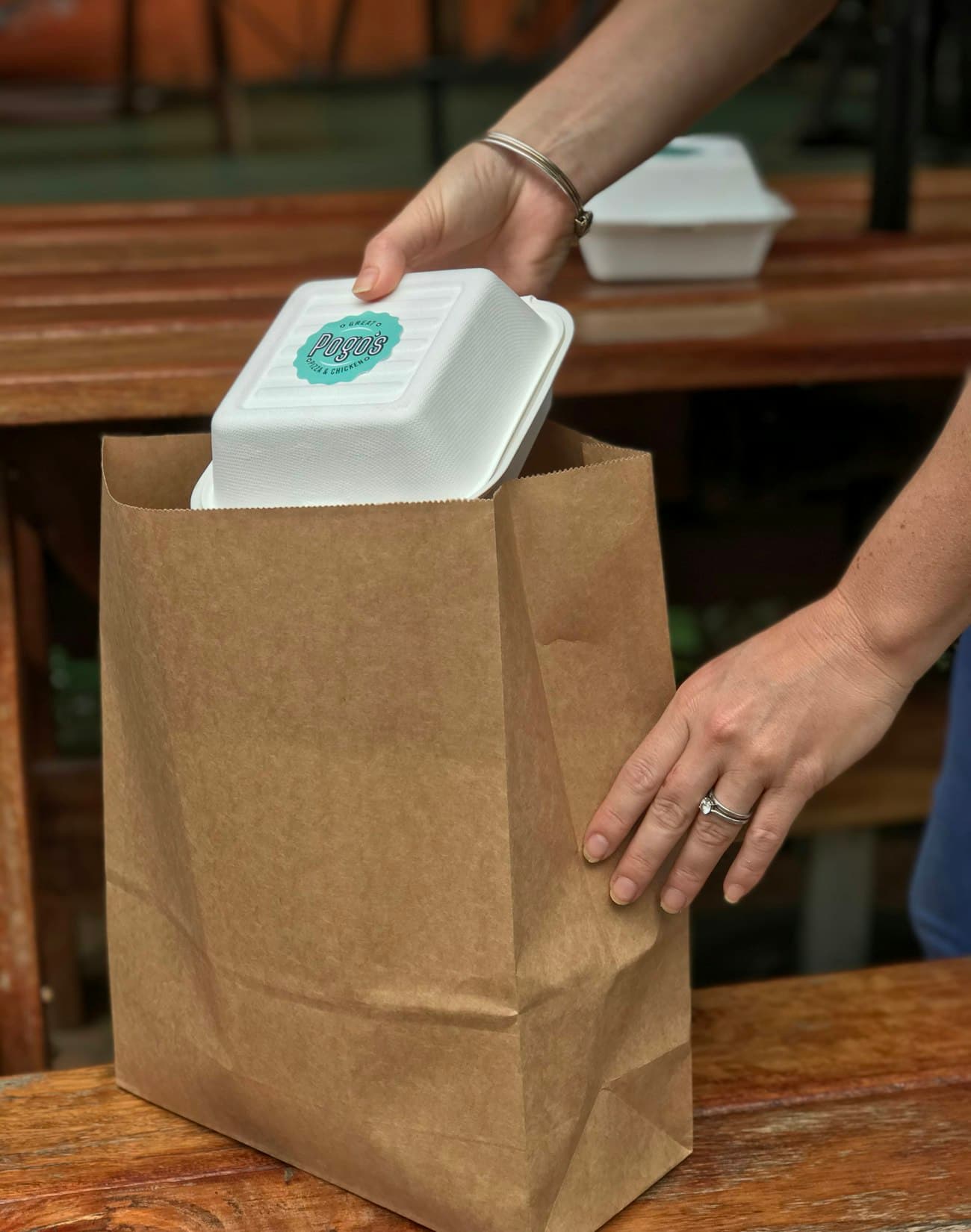Hands packing a takeaway meal into a paper bag
